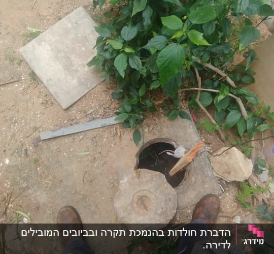 אדם עומד ליד פתח ביוב עם מכסה פתוח